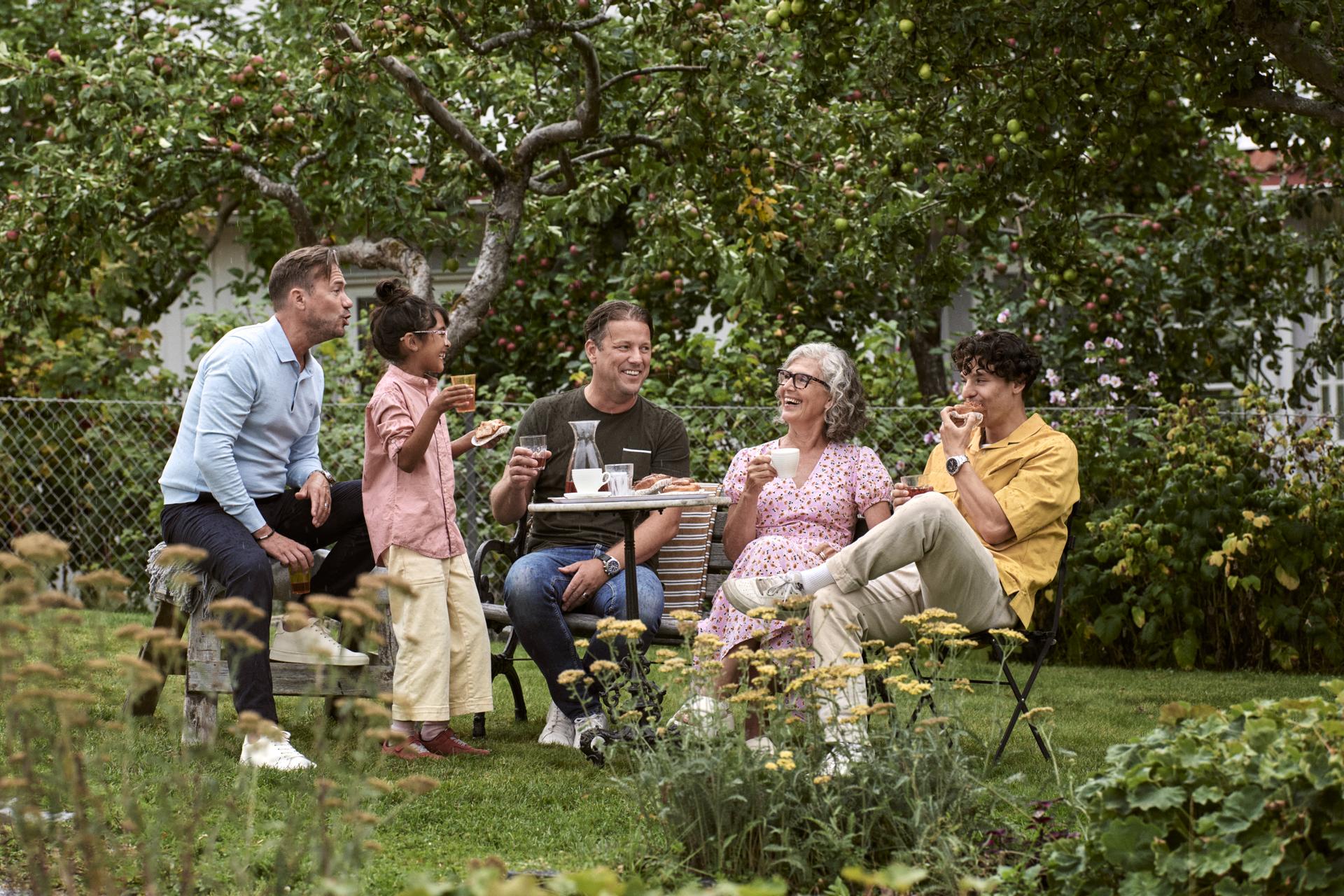 Familj och vänner som har picknick i trädgården