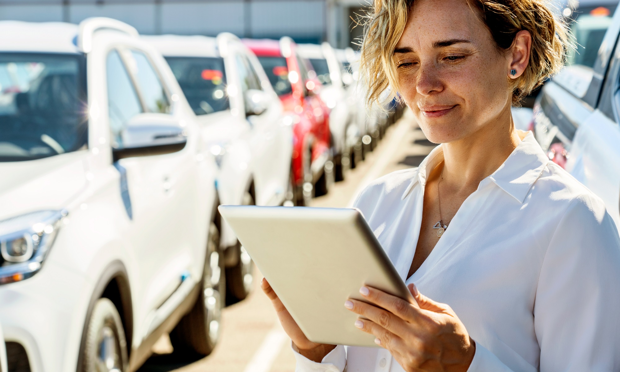 Woman with tablet in front of group of cars
